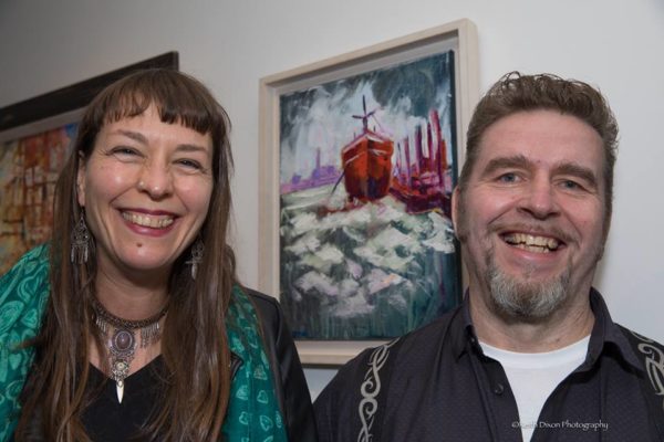 Anja & Rod Coyne grinning in front of Rod's "Red Hull" painting at the official (pardon the pun) launch. Photo by Keith Dixon.