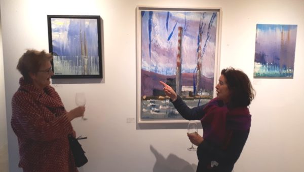 Coyne's "Pigeon House" collection kept visitors rapt with his contemporary take on Dublin Bay's icon skyline. Two Dublin Docklands visitors in animated discussion before three canvases from this singular collection.