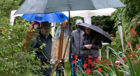 Workshop host, Rod Coyne, completes his painting demo for eager students. The umbrellas are up but spirits remain un-dampened.