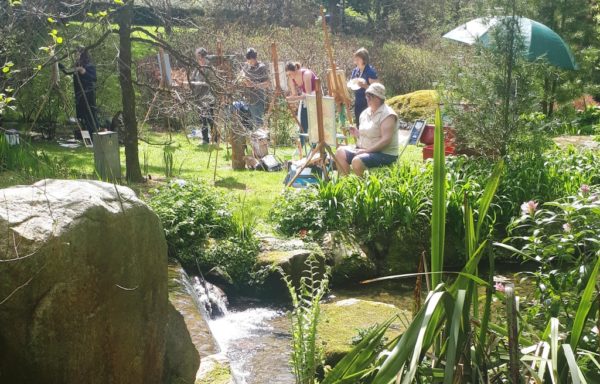 A Photo of students painting in the sunshine beside a tranquil stream in Knocanree Gardens, Avoca.