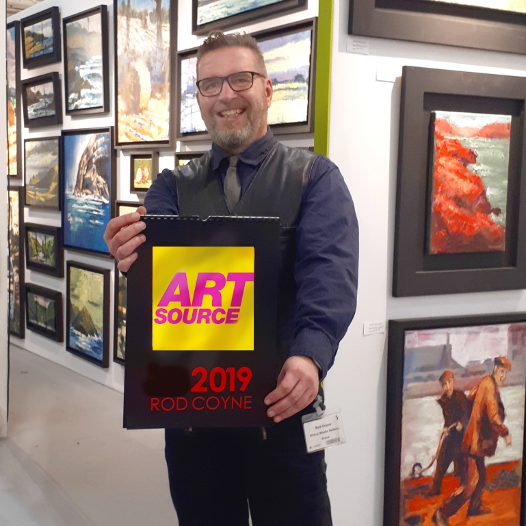 Rod Coyne photographed holding a sign for RDS in Art Source 2019