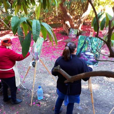 Photo of two students depicting a carpet of pink petals at the Kilmacurragh outdoor painting workshop.