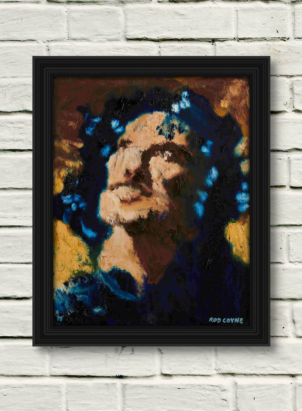 artist rod coyne's portrait "Angel Gabriel" is shown here on a white brick wall in a black frame.